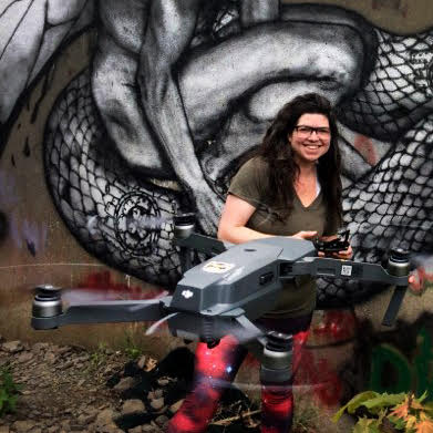 Shira Evergreen piloting her drone in front of a mural